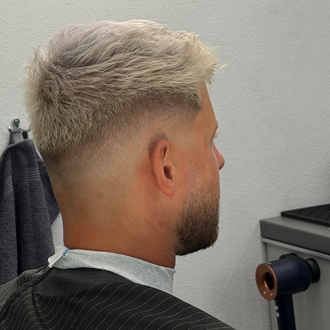 Svetlý skin fade s krátkym textúrovaným vrchom a bradou — strihal Ján