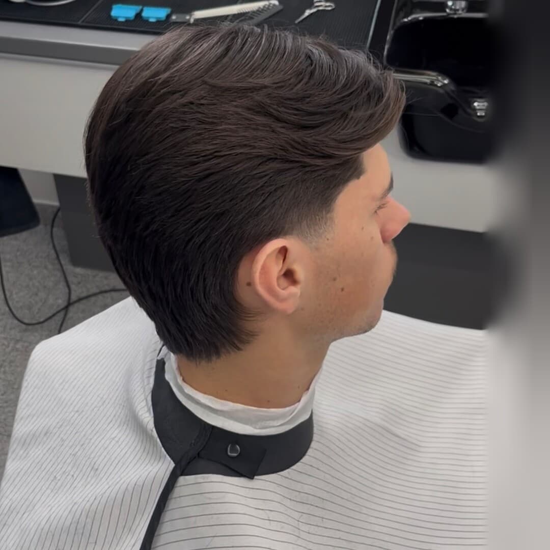 Dlhší vrch učesaný dozadu s taperom okolo ucha a na krku, profil — strihal Kristián
