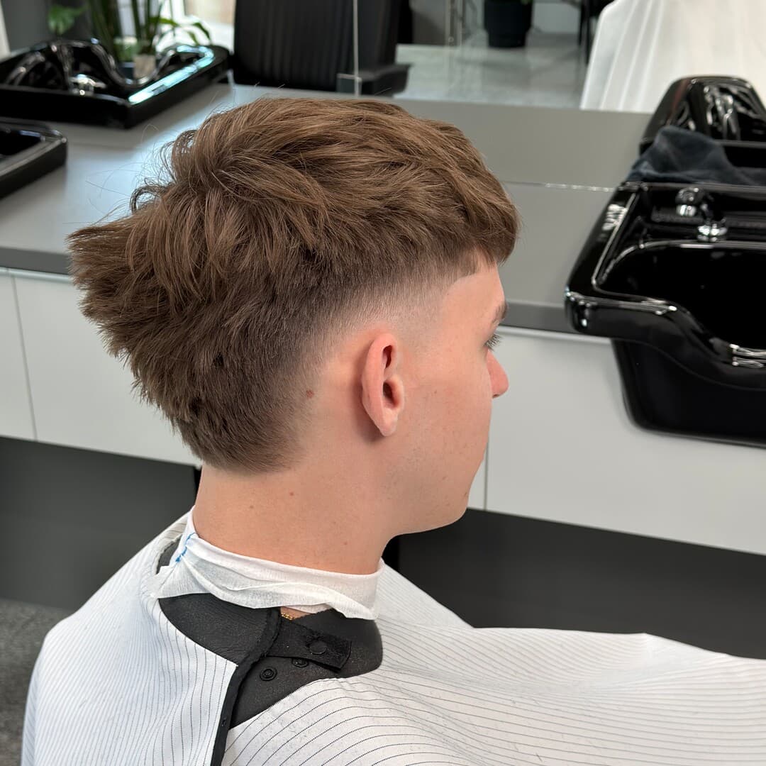 Burst mohawk crop — textúrovaný vrch a burst fade okolo ucha, pohľad z boku zozadu — strihal Marek